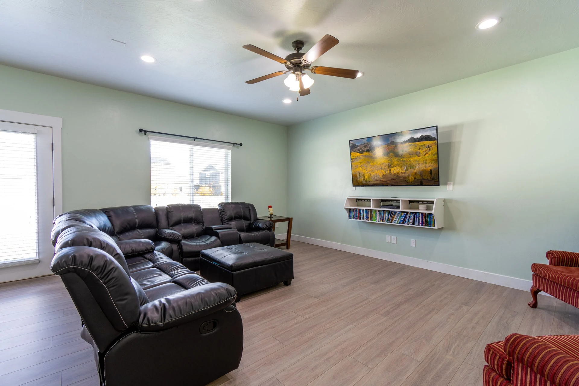 Spacious living room with modern furniture, ceiling fan, and large wall-mounted TV.